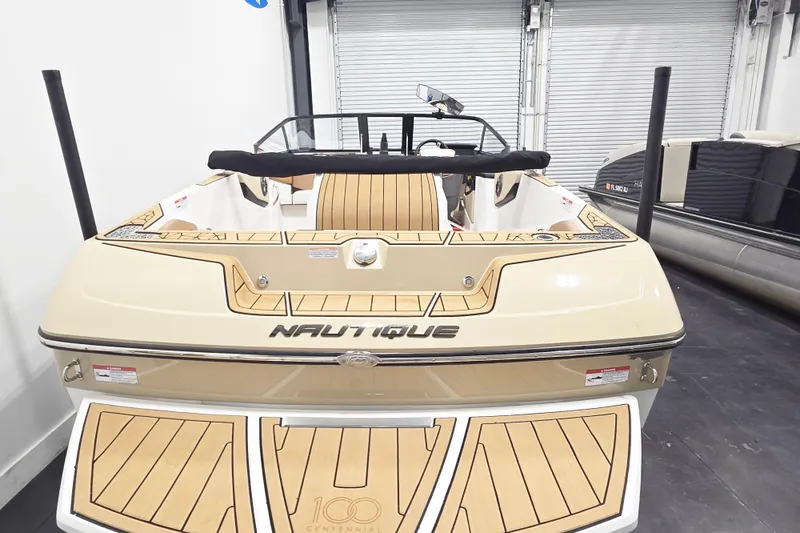 Slide: The Image of 2025 Nautique Ski Nautique boat in showroom, rear view, beige and wood accents. - 7