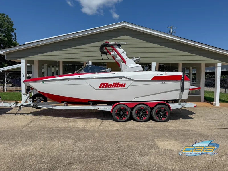 The Image of 2021 Malibu M240 boat with red accents docked in a marina. - 0