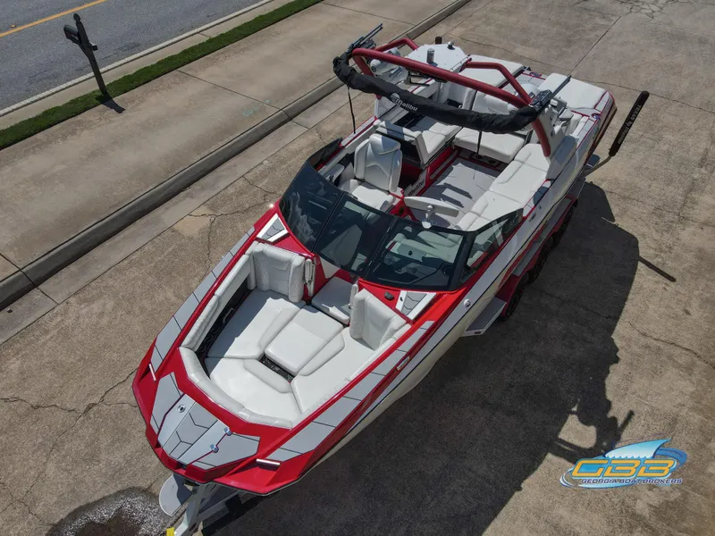 Slide: The Image of 2021 Malibu M240 boat with red and white design, parked on concrete surface. - 15