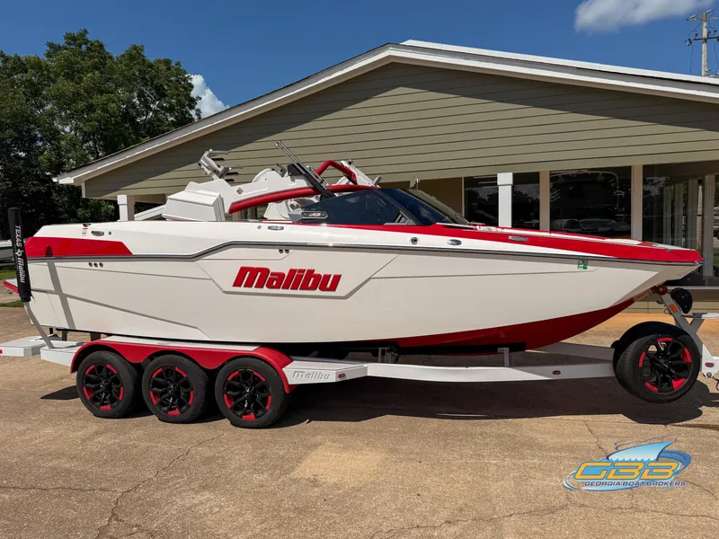 Slide: The Image of 2021 Malibu M240 boat on trailer, red and white design, parked outdoors. - 26