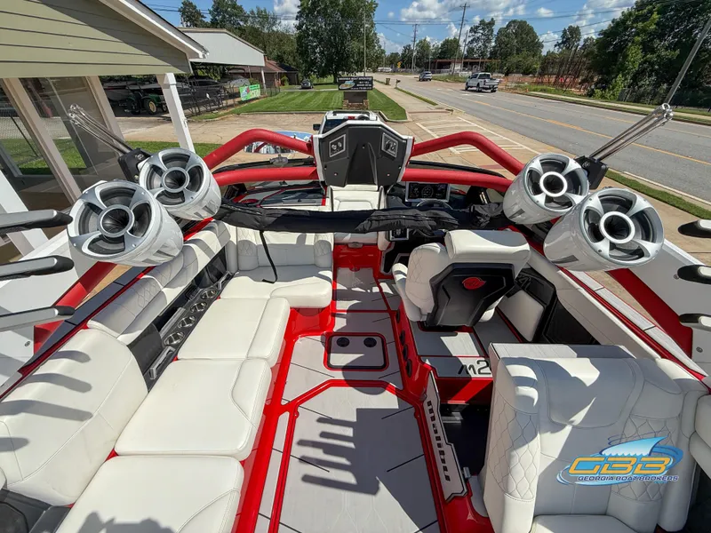 Slide: The Image of Interior of a 2021 Malibu M240 boat with white seating and large speakers. - 28