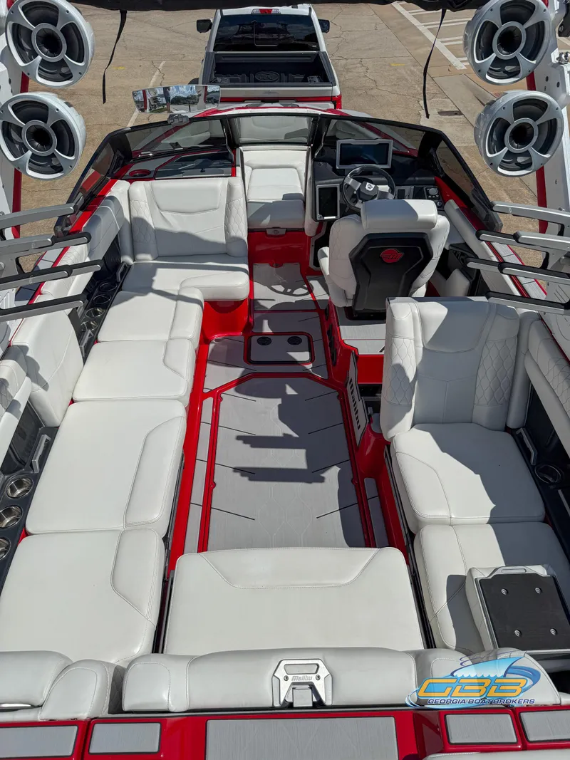 Slide: The Image of 2021 Malibu M240 boat interior with white seating, red accents, and multiple speakers. - 43
