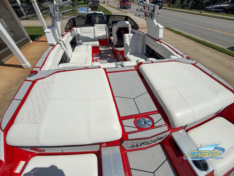 Slide: The Image of 2021 Malibu M240 boat with luxurious white and red seating, docked on a sunny day. - 44