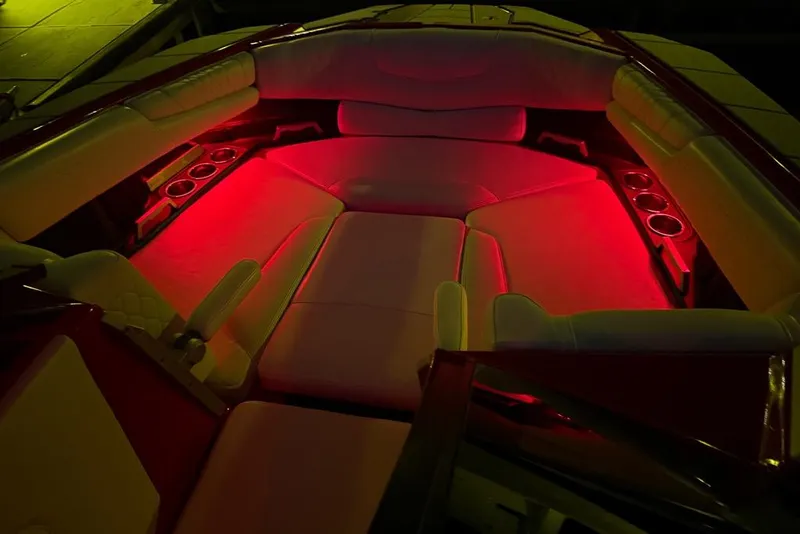 Slide: The Image of 2021 Malibu M240 boat interior with red ambient lighting and cup holders. - 46