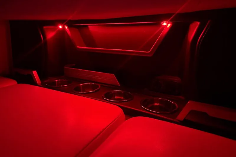 Slide: The Image of Red-lit interior of a 2021 Malibu M240 boat with cup holders and seating. - 48