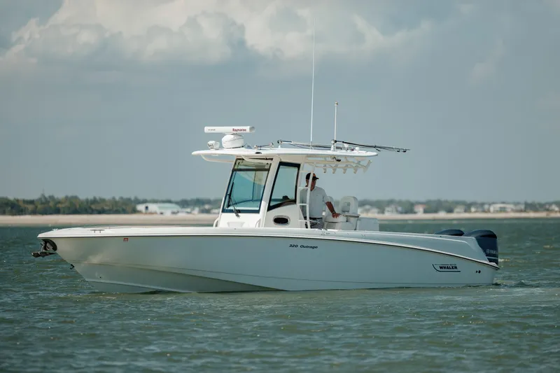Slide: The Image of 2013 Boston Whaler 320 Outrage boat cruising on calm waters under a cloudy sky. - 18