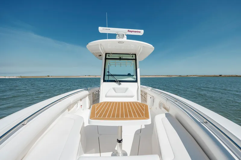 Slide: The Image of 2013 Boston Whaler 320 Outrage boat on calm water, featuring a sleek deck and seating area. - 42