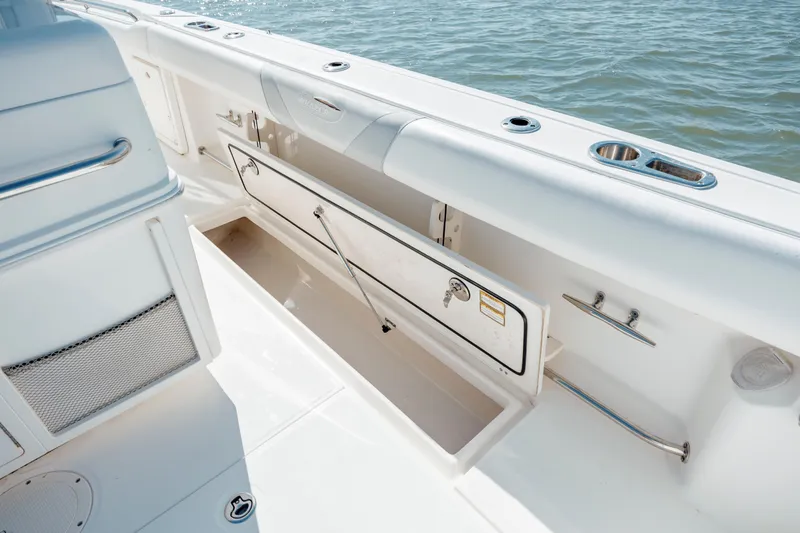 Slide: The Image of 2013 Boston Whaler 320 Outrage boat interior with open storage compartment, near water. - 48