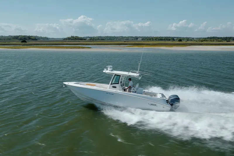 Slide: The Image of 2013 Boston Whaler 320 Outrage cruising on open water near a scenic shoreline. - 5