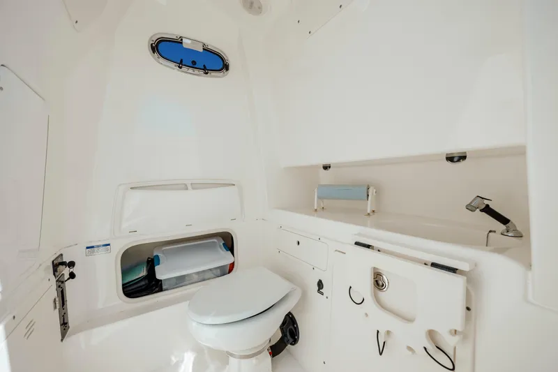 Slide: The Image of 2013 Boston Whaler 320 Outrage boat interior with toilet and storage compartments. - 51