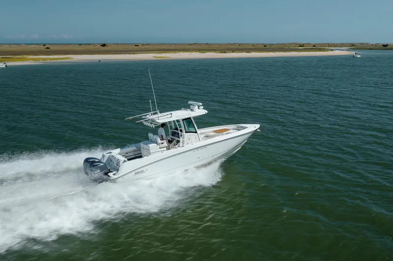 Slide: The Image of 2013 Boston Whaler 320 Outrage cruising on open water near a sandy shoreline. - 8