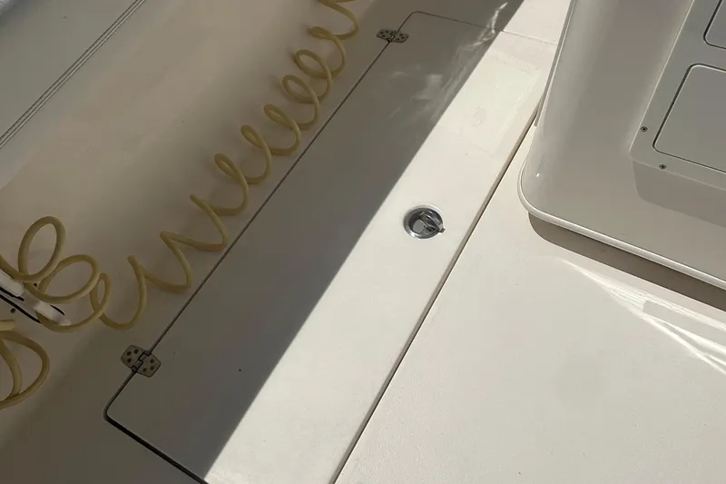 Slide: The Image of 2023 Cobia 262 Center Console deck with storage compartment and coiled hose. - 31