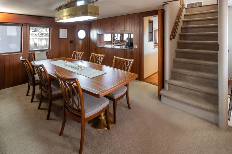 Slide: The Image of Luxurious dining area on 1974 Willard 1201 yacht with elegant wooden furniture and carpeted stairs. - 45
