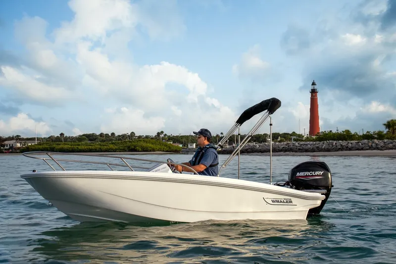 Slide: The Image of 2026 Boston Whaler 130 Super Sport boat on water near lighthouse, under blue sky. - 4