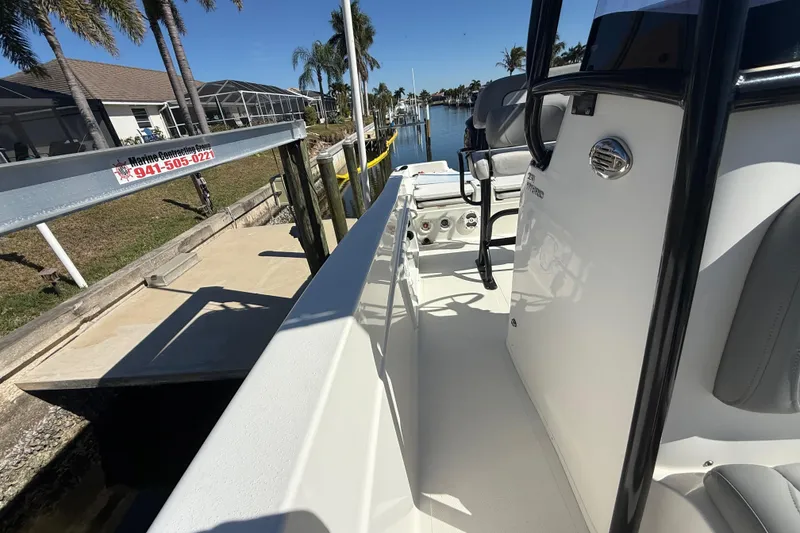Slide: The Image of 2022 NauticStar 231 Hybrid boat docked by a canal with palm trees. - 12