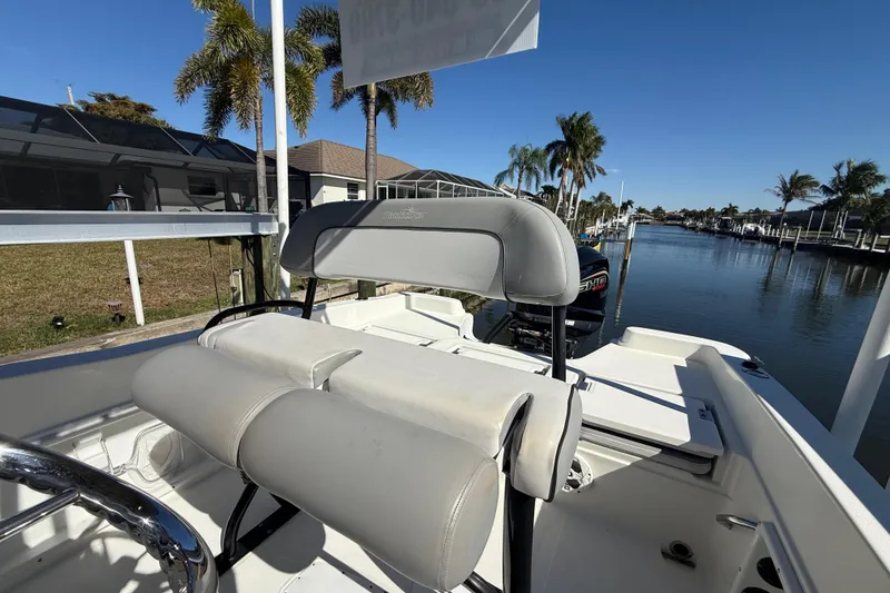 Slide: The Image of 2022 NauticStar 231 Hybrid boat interior with seating, docked by a scenic waterfront. - 14