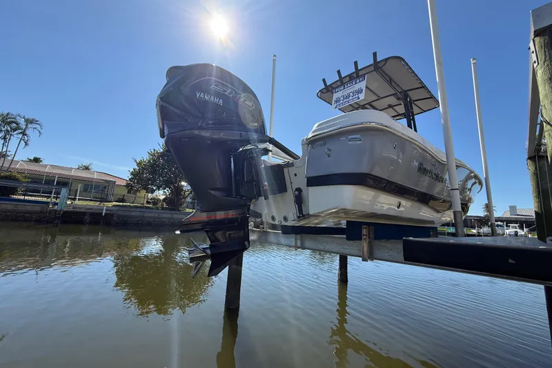 Slide: The Image of 2022 NauticStar 231 Hybrid boat with Yamaha engine on lift, sunny day. - 2