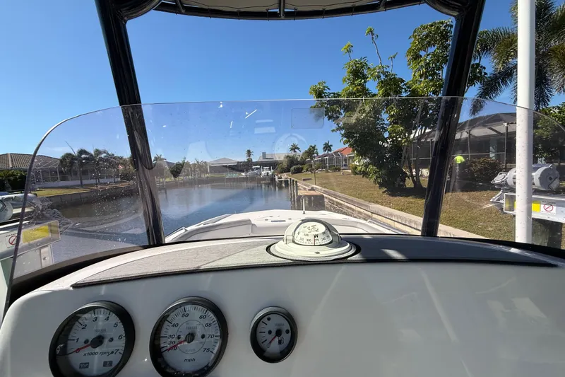 Slide: The Image of 2022 NauticStar 231 Hybrid boat dashboard view, navigating a sunny canal. - 22