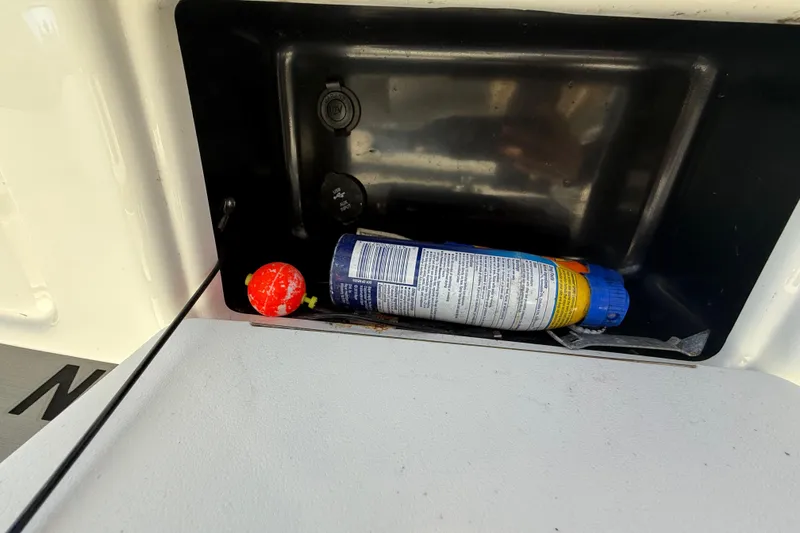 Slide: The Image of Storage compartment on 2022 NauticStar 231 Hybrid boat with canister and red ball. - 23