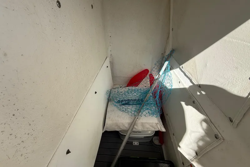 Slide: The Image of Storage compartment in 2022 NauticStar 231 Hybrid boat with fishing net and life jacket. - 25