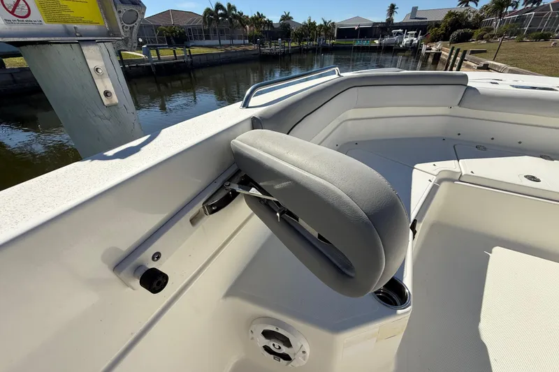Slide: The Image of 2022 NauticStar 231 Hybrid boat interior with seating and cup holder, docked by waterfront. - 34