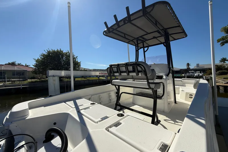 Slide: The Image of 2022 NauticStar 231 Hybrid boat with T-top, docked under clear blue sky. - 4