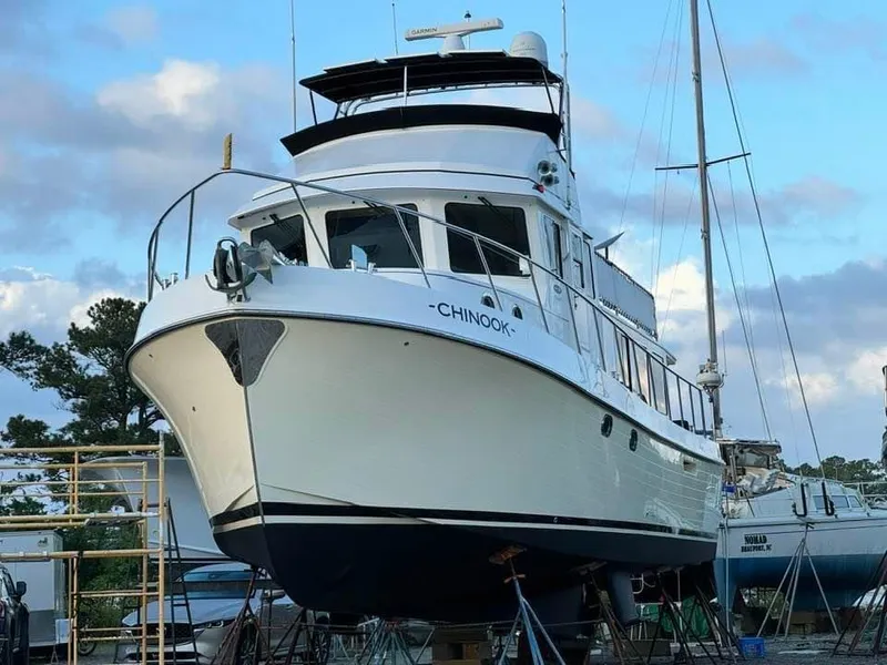 Slide: The Image of 2010 American Tug 49 Limited yacht on dry dock, named "Chinook," under a blue sky. - 16