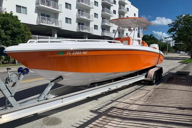 The Image of 2006 Renegade 32 Cuddy boat in vibrant orange on a trailer, urban background. - 0