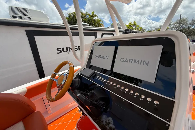 Slide: The Image of 2006 Renegade 32 Cuddy boat dashboard with Garmin navigation systems and wooden steering wheel. - 25