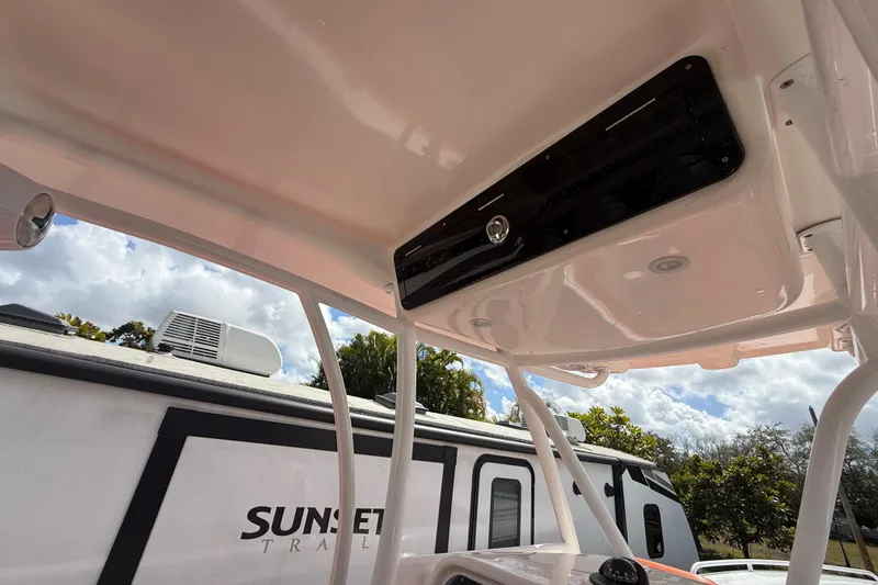 Slide: The Image of 2006 Renegade 32 Cuddy boat interior with overhead storage, near a trailer and trees. - 28