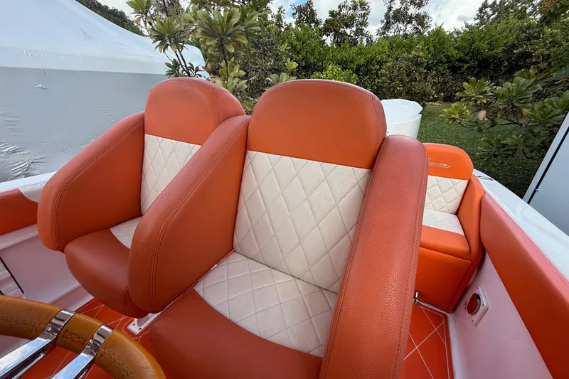 Slide: The Image of Orange and white seating on 2006 Renegade 32 Cuddy boat, surrounded by greenery. - 30