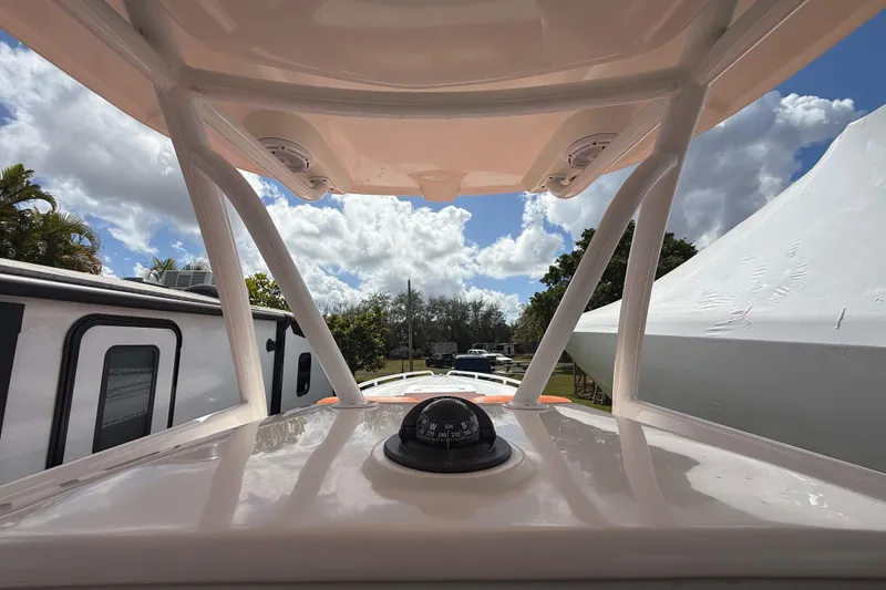 Slide: The Image of 2006 Renegade 32 Cuddy boat helm with compass, under a partly cloudy sky. - 32