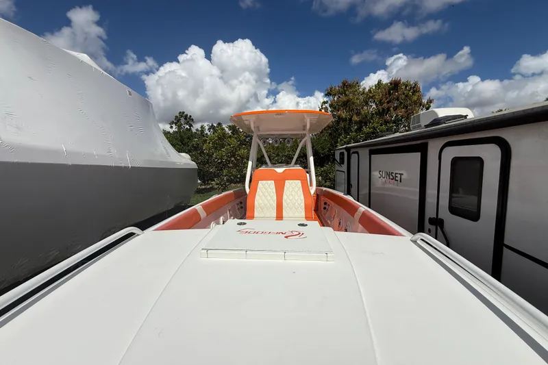 Slide: The Image of 2006 Renegade 32 Cuddy boat with orange accents, parked outdoors under a blue sky. - 49