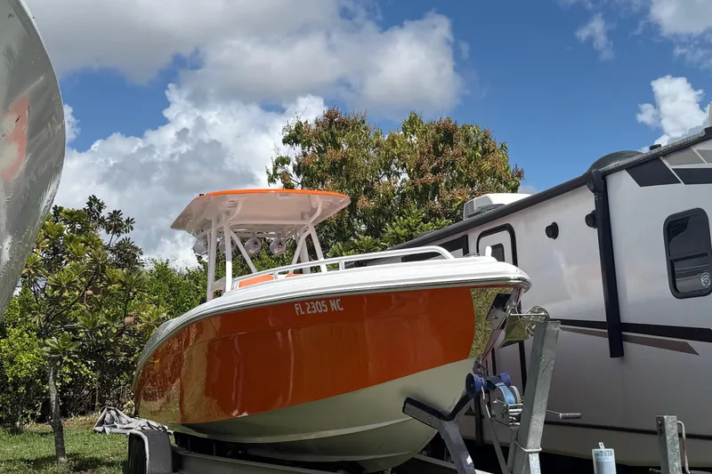 Slide: The Image of 2006 Renegade 32 Cuddy boat with orange hull on trailer, parked beside RV. - 60