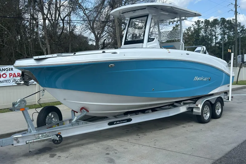 The Image of 2025 Hurricane Center Console 24 OB boat on trailer, blue and white design, parked outdoors. - 0