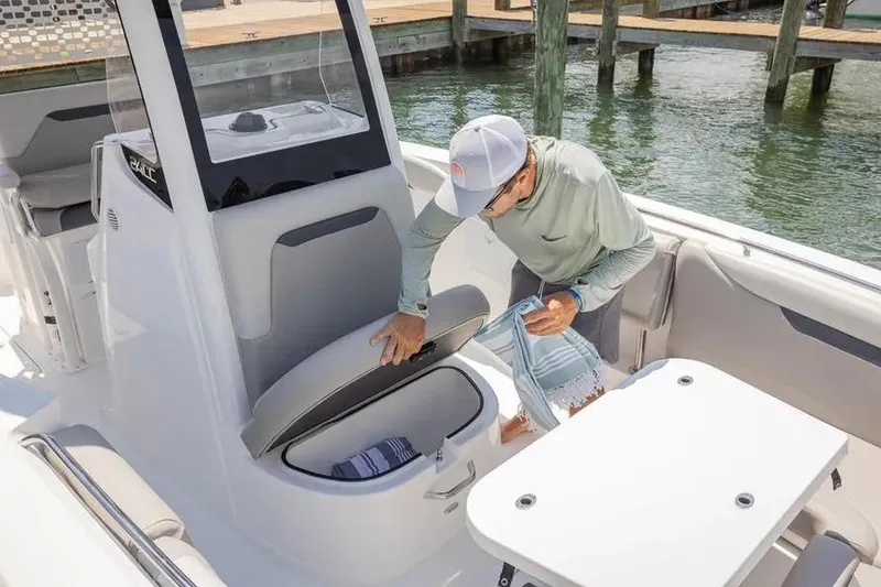 Slide: The Image of Man accessing storage on 2025 Hurricane Center Console 24 OB boat at dock. - 53