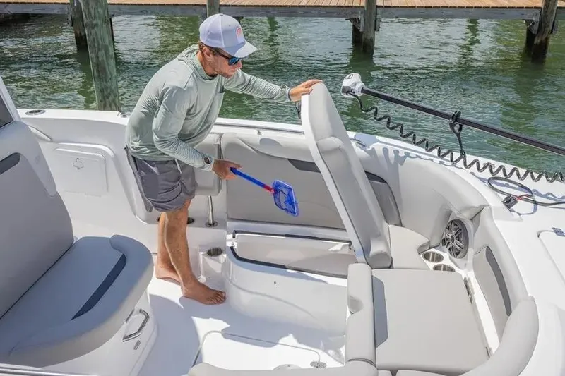 Slide: The Image of Man cleaning 2025 Hurricane Center Console 24 OB boat interior with a net. - 54
