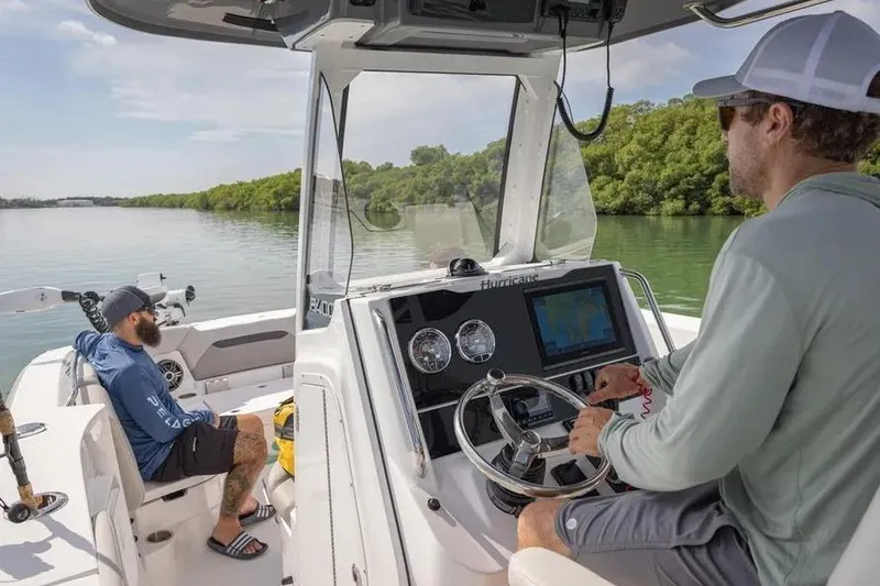 Slide: The Image of Two people on a 2025 Hurricane Center Console 24 OB boat navigating a calm waterway. - 55