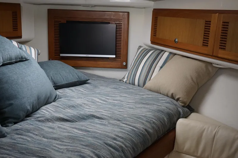 Slide: The Image of 2005 Cabo 35 Express cabin interior with cozy bedding and wall-mounted TV. - 22