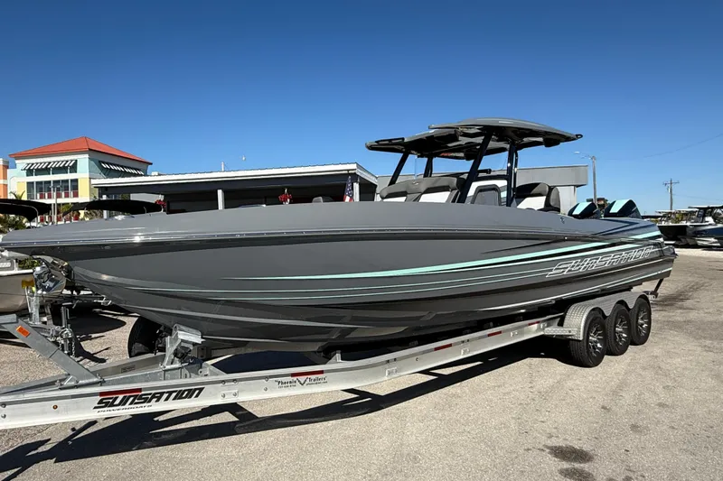 The Image of 2026 Sunsation 32 CCX powerboat on trailer, sleek gray design under clear blue sky. - 1