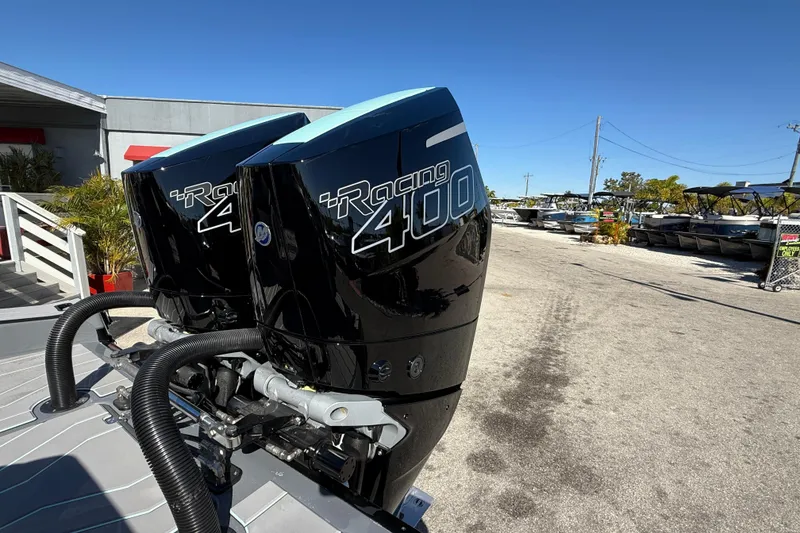 Slide: The Image of Twin Racing 400 outboard engines on a 2026 Sunsation 32 CCX boat, parked outdoors. - 12