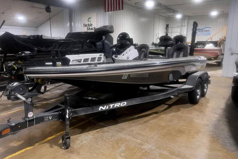 The Image of 2021 Nitro Z18 boat in showroom, featuring sleek design and dual-axle trailer. - 1