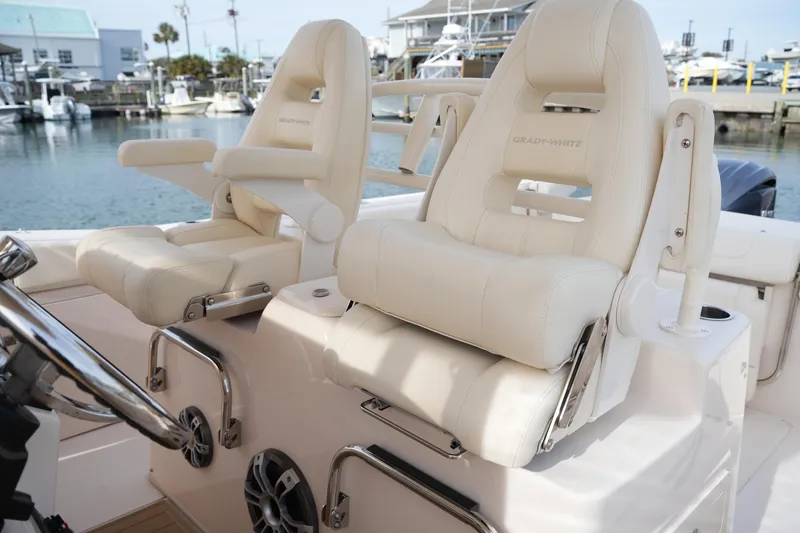Slide: The Image of 2023 Grady-White Canyon 306 boat seats, luxurious white leather, marina background. - 23