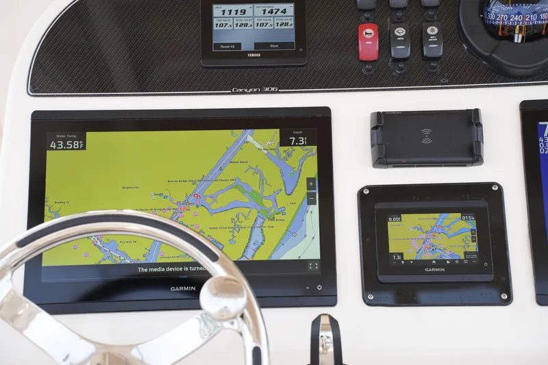 Slide: The Image of 2023 Grady-White Canyon 306 dashboard with Garmin navigation displays and controls. - 32