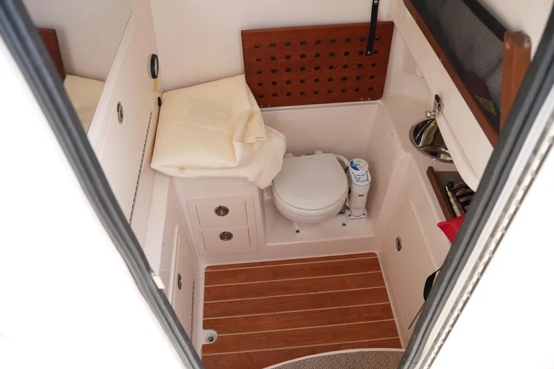 Slide: The Image of 2023 Grady-White Canyon 306 boat interior with compact bathroom and wooden flooring. - 34