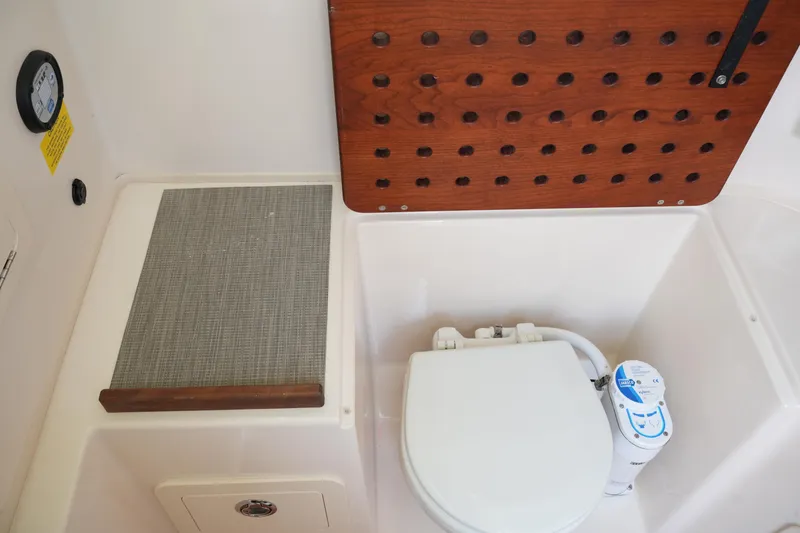 Slide: The Image of 2023 Grady-White Canyon 306 boat interior with toilet and wooden panel. - 35