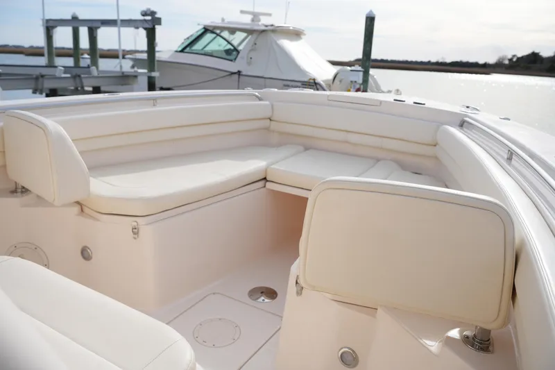 Slide: The Image of 2023 Grady-White Canyon 306 boat interior with cushioned seating, docked by the water. - 38
