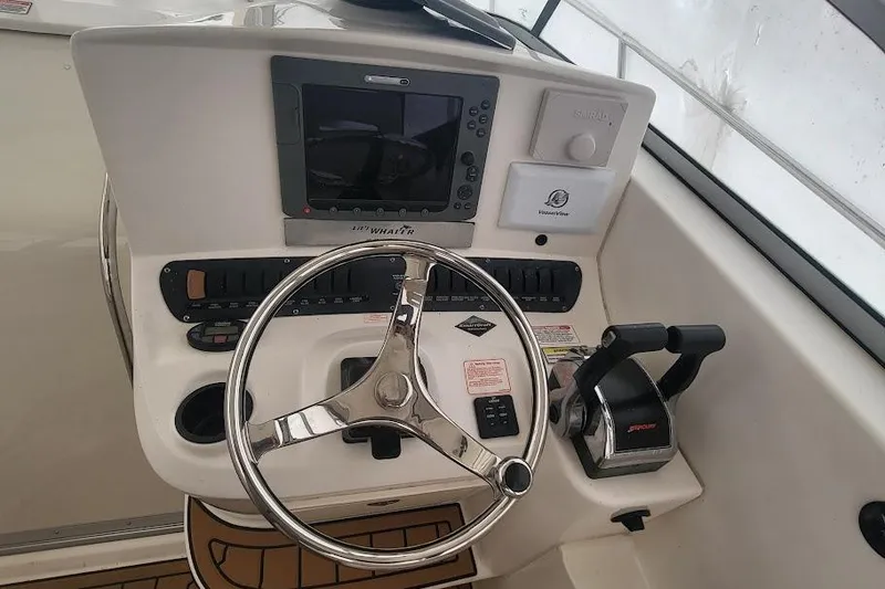 Slide: The Image of 2004 Boston Whaler 305 Conquest helm with steering wheel and control panel. - 18