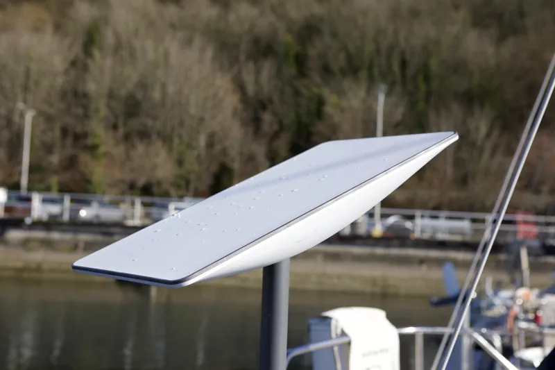 Slide: The Image of Satellite dish on a 1992 Hunter 33.5 boat, docked near a wooded shoreline. - 26