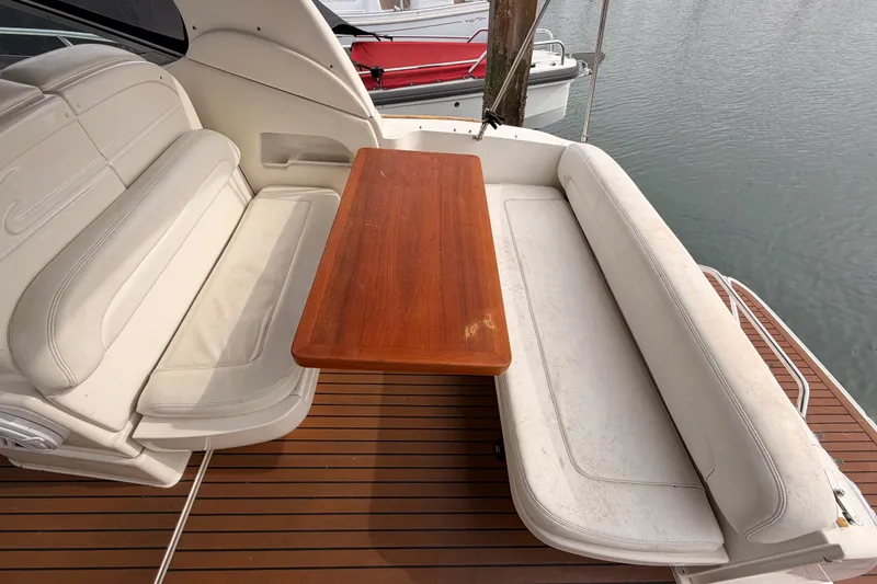 Slide: The Image of 2005 Sea Ray 300 Sundancer boat interior with white seating and wooden table. - 12